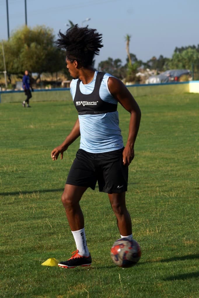 Jogador em treino no campo com colete de monitorização GPS STATSports.